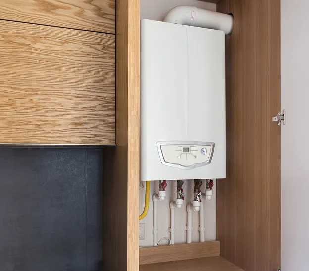 Chaudière à condensation blanche à gaz dans un placard en bois ouvert à Boulogne-Billancourt en Hauts-de-Seine 92